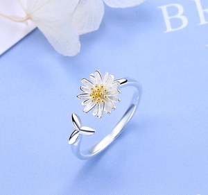 Detail van verstelbare madeliefjes ring met zilveren bladeren op blauw getextureerd papier