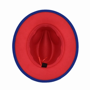 Detail view of red wide-brim fedora hat with blue binding and cotton blend material label