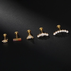 F136 Titanium gold leaf and zircon cartilage piercing studs set on dark background