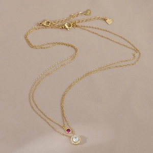 Macro shot of double-layer gold necklace featuring ruby-red and white zircon pendants