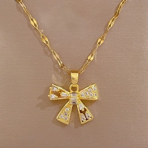 Macro detail of gold-plated hollow bow pendant featuring sparkling zircon stones
