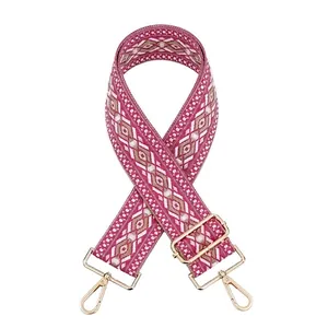 Detail of adjustable woven wide purse strap with pink geometric ethnic pattern and gold hooks