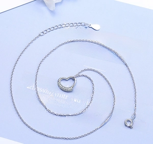 Detail of silver heart pendant necklace with shimmering crystals on blue background