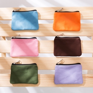 Minimalist canvas coin pouches in six colors with zippers on light wooden background