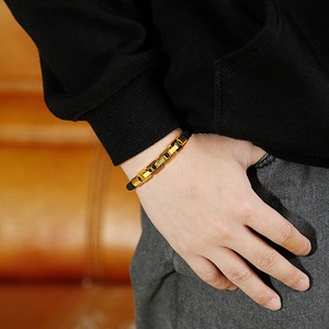 Men's trendy gold stainless steel chain bracelet shown worn on a wrist over a leather sofa