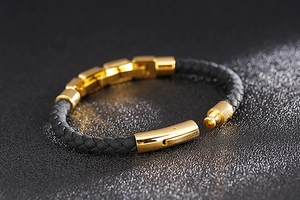 Detail of black braided leather bracelet with polished gold stainless steel clasp