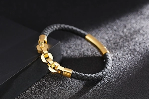 Close-up of black braided leather bracelet with gold polished chain and metal accents