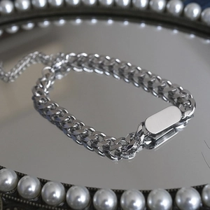 Silver Cuban link bracelet with oval tag on pearl mirrored tray in a punk hip hop style