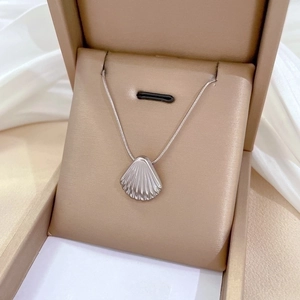 Minimalist silver shell pendant necklace made of titanium steel in a beige jewelry box