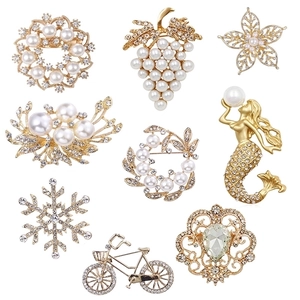 Set of 9 gold-tone floral and pearl brooches with rhinestones on a white background