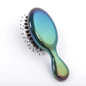 Detail of compact hairbrush featuring a metallic blue-gold gradient finish and nylon bristles