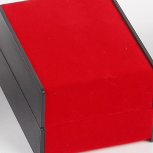 Red velvet jewelry box with black trim and slanted design for watches and bracelets