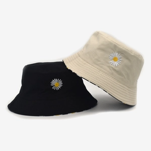 Detailed view of white daisy embroidery on black and beige cotton sun hats