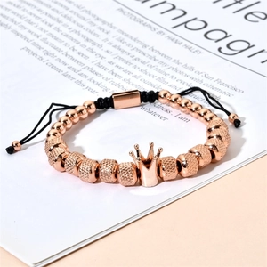 Macro detail of rose gold beads and crown charm on a black adjustable braided bracelet