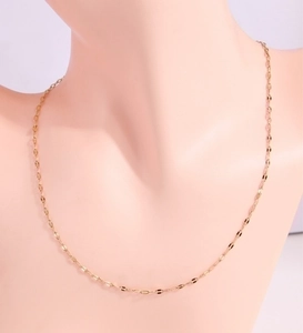 Detail of faceted gold chain links on a minimalist necklace displayed on a mannequin