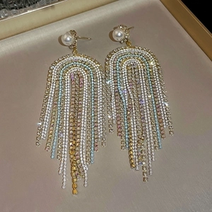 Macro shot of long fringe earrings with colorful rhinestones and pearls on velvet tray