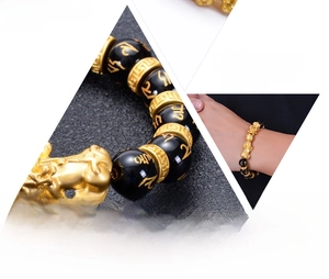 Macro detail of obsidian bead bracelet with golden Pixiu and engraved mantra symbols