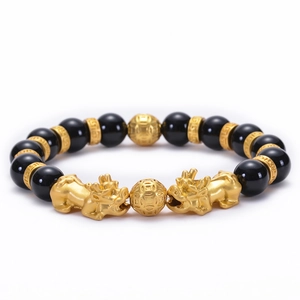 Detailed view of black onyx beads and golden Pi Xiu charm on a stretch bracelet