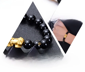Detailed view of obsidian beads with gold mantras and Pi Xiu charm on a stretch bracelet