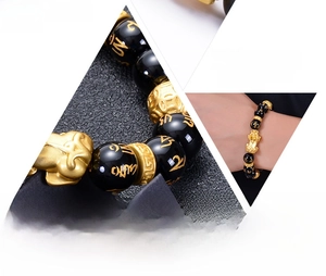 Macro detail of obsidian bead bracelet with golden Pixiu charm and sacred mantra symbols