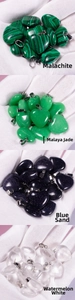 Detail of heart-shaped malachite, jade, and quartz pendants held in a gloved hand