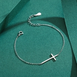 Minimalist S925 sterling silver cross bracelet with polished finish on a green background