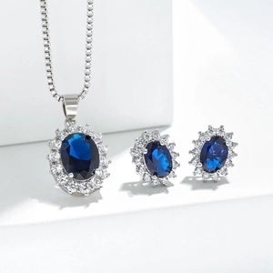 Deep blue sapphire necklace and earrings set with halo crystal accents on white pedestals