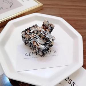 Detail of marble pattern square hair claw clip on a decorative white display tray