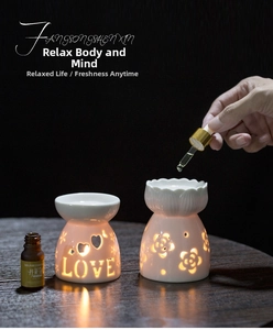 Detail of white ceramic aroma burners with heart and floral cutouts on wood surface