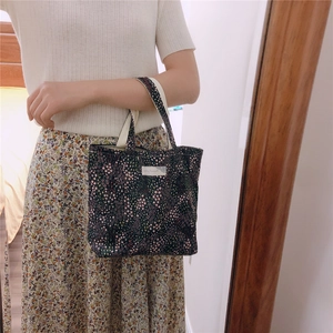 Détail d'un sac à main en coton à fleurs avec fond bleu et motifs floraux roses