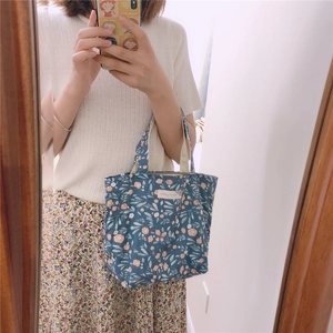 Détail d'un petit sac en toile bleu marine avec motifs floraux et étiquette tissée