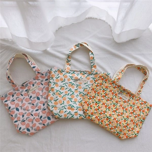 Vue détaillée de trois sacs cabas en toile fleurie sur un tissu blanc texturé
