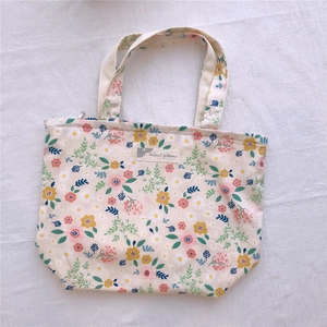 Détail du sac cabas en toile à fleurs avec étiquette et poignées en coton doux