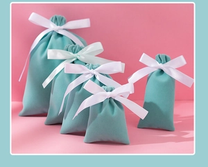 Detail showing various sizes of mint green velvet jewelry pouches with white ribbon bows