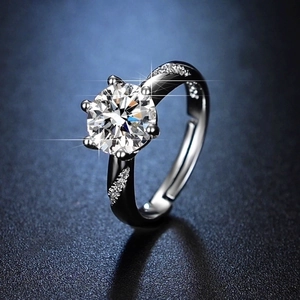 Macro shot of six-prong moissanite ring with twisted pavé band on black surface