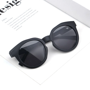 Detail von Kinder-Sonnenbrille in Mattschwarz mit runden grauen Gläsern auf weißer Karte