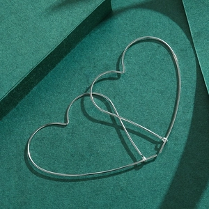 Minimalist S925 sterling silver oversized heart shaped hoop earrings on green background