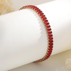 Detail of 18K gold-plated bracelet featuring emerald-cut red zircons on a white display