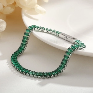Elegant silver tennis bracelet with emerald-cut green zircons on white ceramic plate