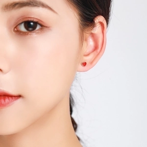 Minimalist S925 sterling silver hollow red heart stud earring on model's earlobe