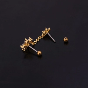 Detail of golden steel ear stud with colorful zircon drop and chain connection