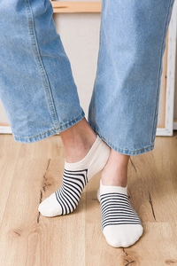 Close-up of white cotton low-cut socks with black stripes on a wooden floor