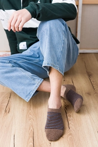 Detailed close-up of brown and navy striped low-cut cotton socks on a male model