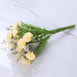 Artificial yellow carnation bouquet with green leaves on marble surface for home decor