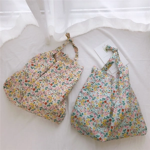Close-up of floral cotton bags with unique knotted handles and soft pleated texture