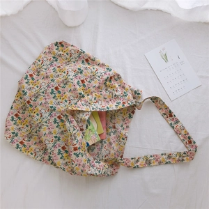 Detail view of floral canvas tote bag with pink flowers and books on white bedding