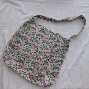 Detailed top view of purple floral canvas tote bag with yellow print on white fabric