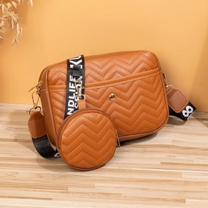 Brown V-quilted crossbody bag detail with lettered strap and round coin purse attachment