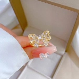 Elegant gold butterfly zircon ring with adjustable band shown on finger over a jewelry box