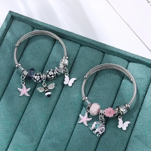 Silver wire charm bracelet with pink enamel elephant and starfish pendants on velvet